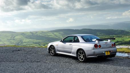 Silver Sports Car Overlooking Serene Landscape in 4K Resolution wallpaper