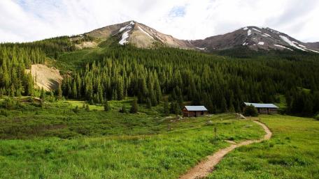Serene Mountain Valley with Lush Greenery and Cabins wallpaper