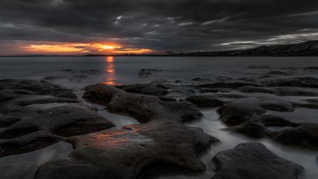 Dramatic Sunset Over Rocky Shoreline wallpaper