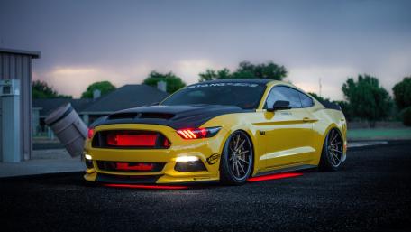 Sleek Yellow Mustang with LED Accents in a Stunning Setting wallpaper