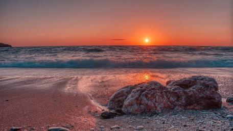 Tranquil Sunset Over Waves and Boulder wallpaper