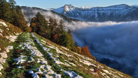 Breathtaking Mountain Landscape with Misty Clouds and Snowy Trails wallpaper