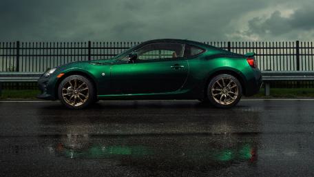 Sleek Green Car on Rainy Road wallpaper