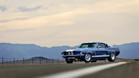 Classic Ford Mustang on Open Road Under Scenic Sky wallpaper