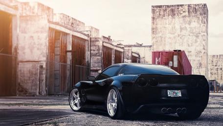 Sleek Black Sports Car in Abandoned Warehouse Scene wallpaper