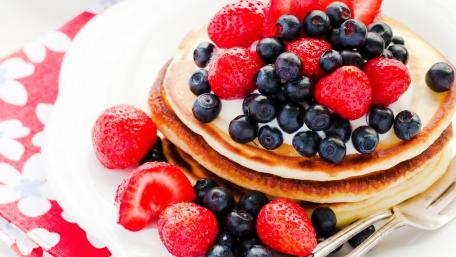 Delicious Pancakes Topped with Fresh Berries and Whipped Cream wallpaper