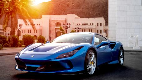 Sleek Blue Ferrari Under Golden Sunset Rays wallpaper