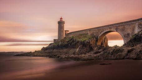 Serene Lighthouse at Sunset over Tranquil Waters wallpaper