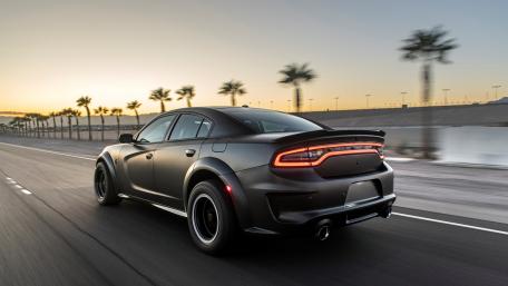 Sleek Black Car Driving into Sunset wallpaper