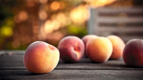Peaches on a Wooden Table Under Soft Lighting wallpaper