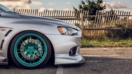 Sleek Silver Car with Vibrant Turquoise Wheels and Scenic Background wallpaper