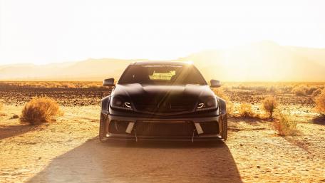 Sleek Black Car in a Desert Sunset wallpaper