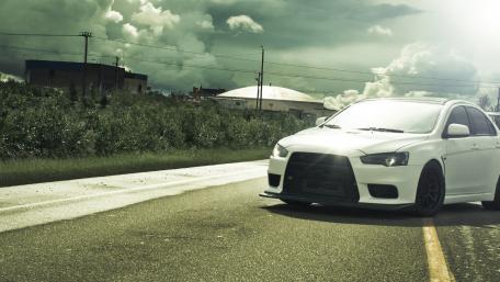Sleek White Car on a Remote Road Under Dramatic Skies wallpaper