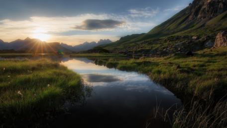 Tranquil Sunrise Over Serene Lake Beyond Mountains wallpaper