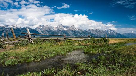 Breathtaking Mountain Landscape with Verdant Pasture and Stream wallpaper