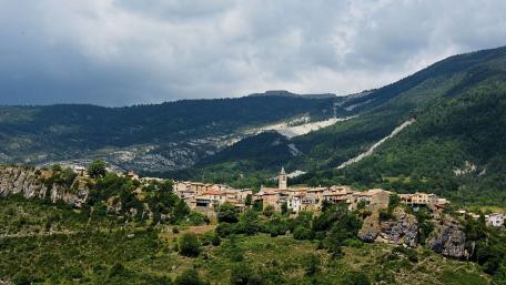 Scenic Village Surrounded by Majestic Mountains and Lush Greenery wallpaper