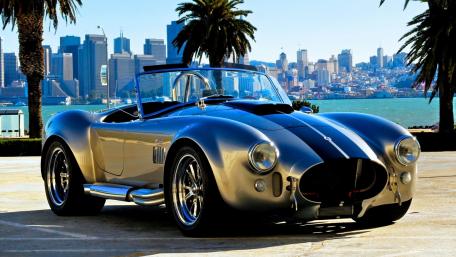 Classic Shelby Cobra Against a City Skyline View wallpaper