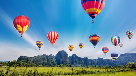 Colorful Hot Air Balloons Over Scenic Landscape wallpaper