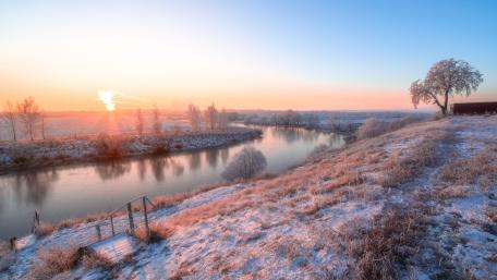 Serene Winter Sunrise Over a Frozen River wallpaper