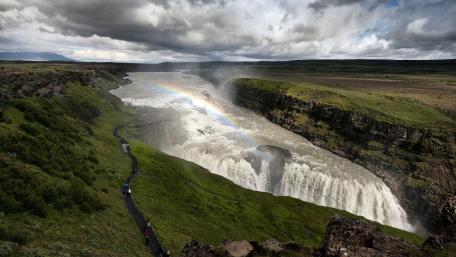 Majestic Waterfall Amidst Lush Greenery and Rainbows wallpaper