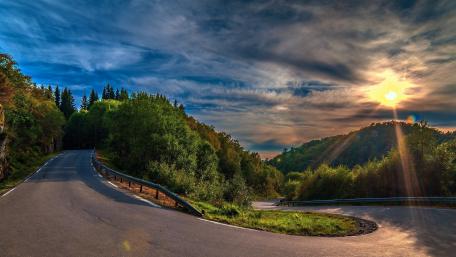 Winding Road Through Lush Greenery at Sunset wallpaper