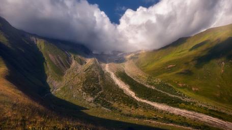 Majestic Mountain Valley Under Cloudy Sky wallpaper