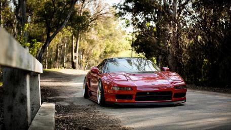 Sleek Red Sports Car on a Quiet Roadway wallpaper