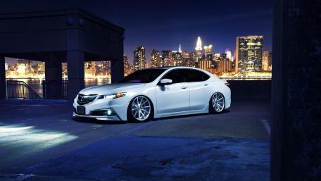 Sleek White Car Against City Skyline at Night wallpaper