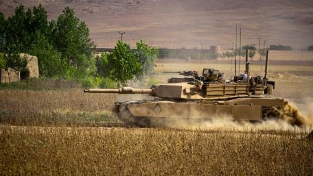 Powerful Tank in Action Amidst Desert Landscape wallpaper