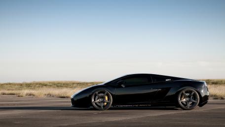 Sleek Black Sports Car on Open Terrain wallpaper