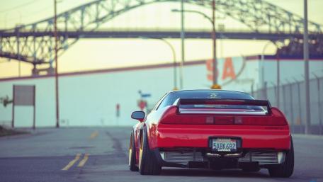 Sleek Red Car by the Bridge Scene wallpaper