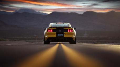 Bold Yellow Mustang on Open Road at Sunset wallpaper