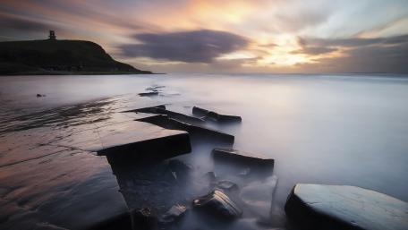 Serene Coastal Sunset Over Rocky Shoreline wallpaper