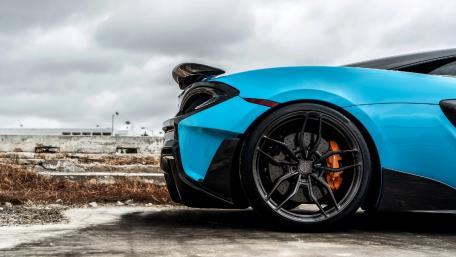 Striking Blue Sports Car Against Dramatic Sky wallpaper