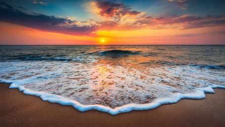 Serene Beach Sunset Over Foamy Waves wallpaper