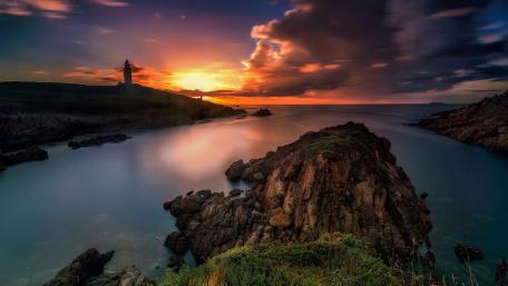 Serene Coastal Sunset Over Rocky Shoreline wallpaper