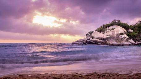 Serene Purple Sunset Over Tranquil Beach Scene wallpaper
