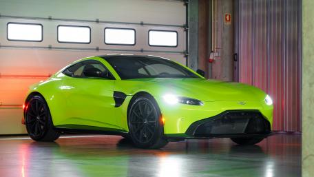 Vibrant Green Aston Martin in Modern Garage Scene wallpaper