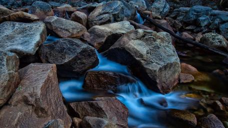 Serenity of a Mountain Stream Flowing Through Rocks wallpaper