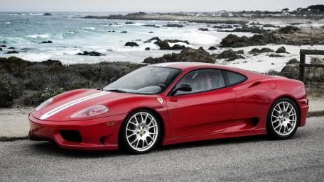 Sleek Red Sports Car by the Ocean Shore wallpaper