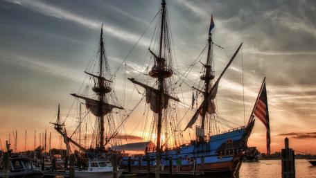 Majestic Sunset Over Historic Ship in Harbor wallpaper