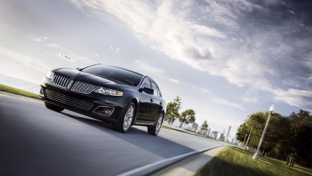 Sleek Black Luxury Car on Scenic Roadway wallpaper