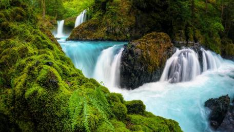Serene Waterfalls Surrounded by Lush Greenery wallpaper