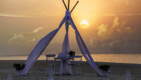 Secluded Beachfront Dining Under a Sunset Sky wallpaper