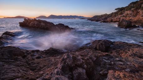 Serene Coastal Sunset Over Rocky Shoreline wallpaper