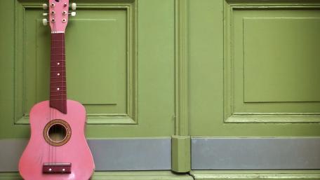 Charming Pink Ukulele Against a Green Backdrop wallpaper