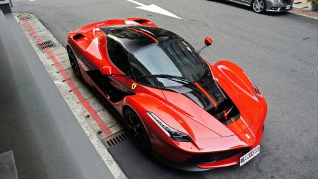 Sleek Red Supercar Stands Out in Urban Setting wallpaper