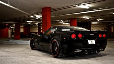 Sleek Black Corvette in Urban Garage Scene wallpaper