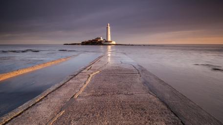 Serene Lighthouse at Dusk Over Tranquil Waters wallpaper