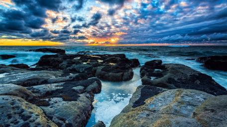 Serene Coastal Sunset Over Rocky Shoreline wallpaper